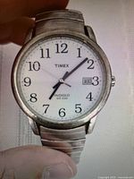 Close-up front view of Timex Easy Reader watch showing white dial, black numerals, date window, and expansion band with visible light scratches.