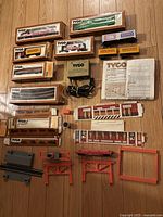 Full overhead view of all Tyco HO scale train cars, tracks, power supply, instruction manual and accessories. Several items remain in original boxes.