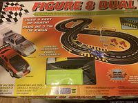 Box and packaging of Artin Figure 8 Dual Rally Road slot car set showing over 9 feet of track, working headlights, and included cars (Porsche 911 GT2 and Nissan 240SX).
