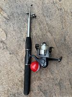 Full fishing rod with reel and bobber on ground