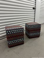 Two cube ottomans showing front and side angles in storage unit with visible detailed patterned fabric upholstery.