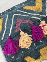 Close-up photo showing the yarn tassels in pink and beige on dark blue geometric patterned pillow cover.