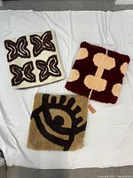 Three tufted throw pillow covers arranged to show designs representing West African Adinkra symbols in earth tone colors.