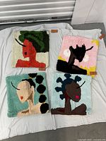 Four colorful tufted throw pillow covers laid out on a white cloth, each with a distinct abstract female profile design.