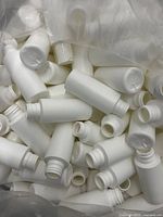 Photo showing a pile of numerous white plastic bottles, highlighting the quantity and uniform shape and size.