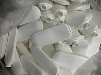 White plastic bottles approximately 6oz each piled together without caps visible.