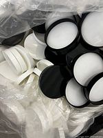 Large quantity of white and black gloss smooth jar lids in clear plastic bags