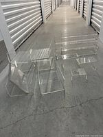 Wide shot showing all acrylic risers laid out on a concrete floor in front of storage unit doors.