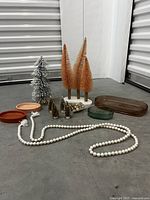 Various decorative items including artificial trees, trays, and pearl garland arranged on a floor