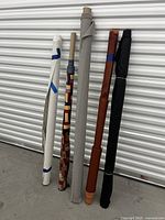 Five fabric rolls leaning against a white metal door, showing variety of colors and patterns.