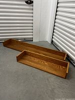 Two solid wood floating oak shelves on storage unit floor, showing natural oak finish and wood grain.