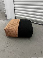 Floor cushion side view showing the rectangular shape and the two-tone fabric design in light brown textured fabric and black plush fabric.