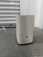 Front view of a white ultrasonic cool mist humidifier with control buttons and power cord visible.