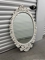 Full view of the large oval mirror with painted white teak wood frame and detailed carvings.