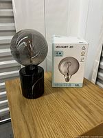 Full view of the marble base lamp alongside the MOLNART LED bulb box on wooden surface.