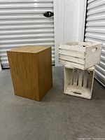 Overall view of the oak wood plinth standing next to two white painted wooden crates stacked, showing scale and condition