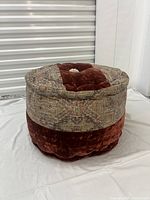 Side view of brand new round floor cushion showing rust velvet top and patterned fabric side.