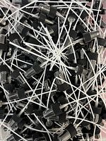 Pile of many black plastic spray bottle tops with attached clear dip tubes and transparent caps