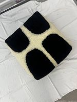 Top angle showing tufted floor cushion with black and cream geometric pattern on a white cloth.