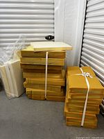 Two large stacks of yellow upholstery foam pieces bundled with straps, showing rectangular foam pieces with varying dimensions and thickness