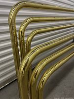 Closeup of curved brass tubes and connections of the bedframe.
