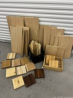 Full lot photo showing multiple sizes of wood panels, small blocks, squares and a container with thin strips.