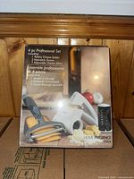 Boxed TRUDEAU 4-piece professional cheese slicing set with rotary cheese grater, two nonstick drums, and adjustable cheese slicer shown on wood background.