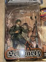 Front view of the Dusty Trail Schwartz army action figure in original packaging with visible accessories including two small hand-held items and one large machine gun with bipod.