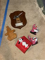Top view of all items showing aircraft plaque, wooden snowman puzzle, Snoopy piggy bank, and two pink Energizer Bunny pencil sharpeners.