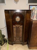 Front view of antique RCA Victor Model 220 floor radio console showing arched wooden cabinet with circular dial, control knobs, and decorative speaker grille.