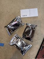 Lot showing three individually wrapped water filter cartridges and instruction leaflet on beige carpet.