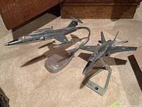 Two metal model airplanes on their curved display stands shown side by side