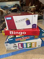 Stacked view of four boxed board games: Toy Story Pictionary, Bingo, Monopoly Junior, and The Game of Life.