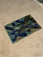 Rectangular glass dish on carpet with swirling colorful patterns in blue, green, beige, and brown tones.
