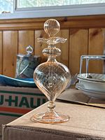 Nachtmann crystal perfume bottle standing on a surface with wood paneling in background, showing its label and elegant shape.