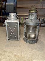 Two antique lamps of different styles placed side by side on a carpeted floor.