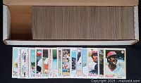 Lot of over 500 cardboard baseball cards stacked inside original Topps box featuring star players including Nolan Ryan and team cards.