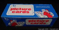 Closed blue and white Topps picture cards vending box with red text and illustrations, showing front and top view of the box.