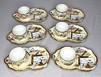 Set of six antique Japanese Kutani porcelain teacups with matching snack plates arranged on a table, showing hand-painted traditional designs and gold accents.
