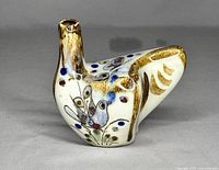 Front left side view of the bird-shaped bud vase showing painted bird and floral designs with a slightly raised neck for flower placement.