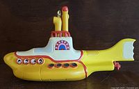 Side view of Yellow Submarine figurine showing Beatles' faces in portholes and red, yellow, white color scheme.