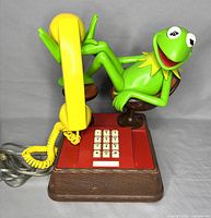 Full image of yellow handset, red and woodgrain base, and Kermit figure in brown chair on base
