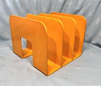 Front angle showing three vertical dividers and front cutout handle of bright orange record holder.