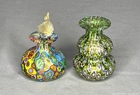 Two Murano millefiori art glass perfume bottles on gray background, one colorful with stopper, one greenish without stopper