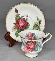 Front view of the teacup placed in front of the saucer, showing detailed rose design and gold trim.
