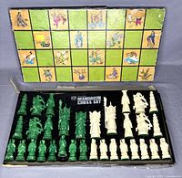 Photo of the full set of green and cream chess pieces arranged in original box with illustrated lid showing Mandarin-style artwork.