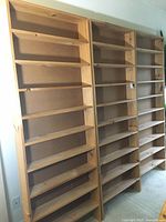 Three tall wooden bookshelves standing next to each other, showing overall front view with multiple shelves.