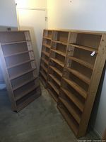 Four smaller wood bookshelves angled and leaning against the wall in a room with visible carpeted floor.