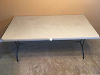 Front view of Lifetime folding table showing textured beige top and black metal folding legs.