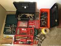 Full view of three toolboxes and assorted tools displayed on carpet including socket sets, clamps, wrenches, hammer, tape, and hand tools